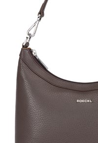 Braune Lederhandtasche mit strukturiertem Oberflächen, Reißverschluss und silbernen Hardware-Details. Markenname "ROECKL" auf der Vorderseite angezeigt.