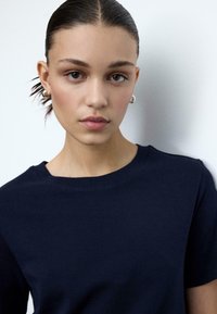 Navyblauw katoenen T-shirt met een klassieke ronde hals en korte mouwen. Gladde textuur met een aangesloten silhouet.