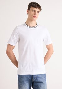 Hvid kortærmet T-shirt lavet af bomuld, med et sort kantet rund halsudskæring og "BOSS" logo detaljer. Minimalistisk design med en afslappet pasform.
