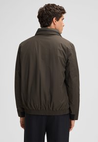 Männer leichte bomberjacke in braun mit hohem kragen, elastischem bund und bündchen; glatte, matte oberfläche und lockere passform.