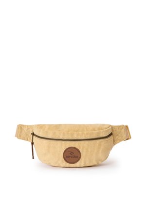 Riñonera beige de pana con compartimento principal con cremallera y correa ajustable, con un parche circular marrón con el logo de Rip Curl.