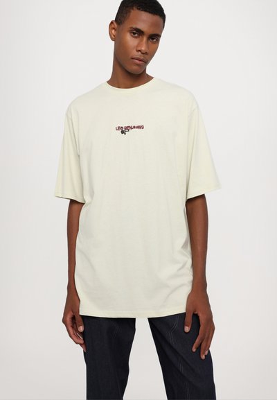 Helles gelbes oversized T-Shirt aus Baumwolle mit kurzen Ärmeln, das ein kleines burgunderfarbenes Logo auf der Brust trägt. Klassischer runder Ausschnitt.