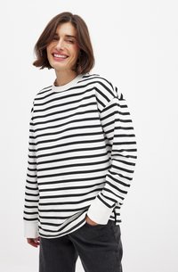 Sweatshirt à manches longues noir et blanc à rayures, avec un col rond. Tissu doux, coupe décontractée, fentes latérales et poignets côtelés.