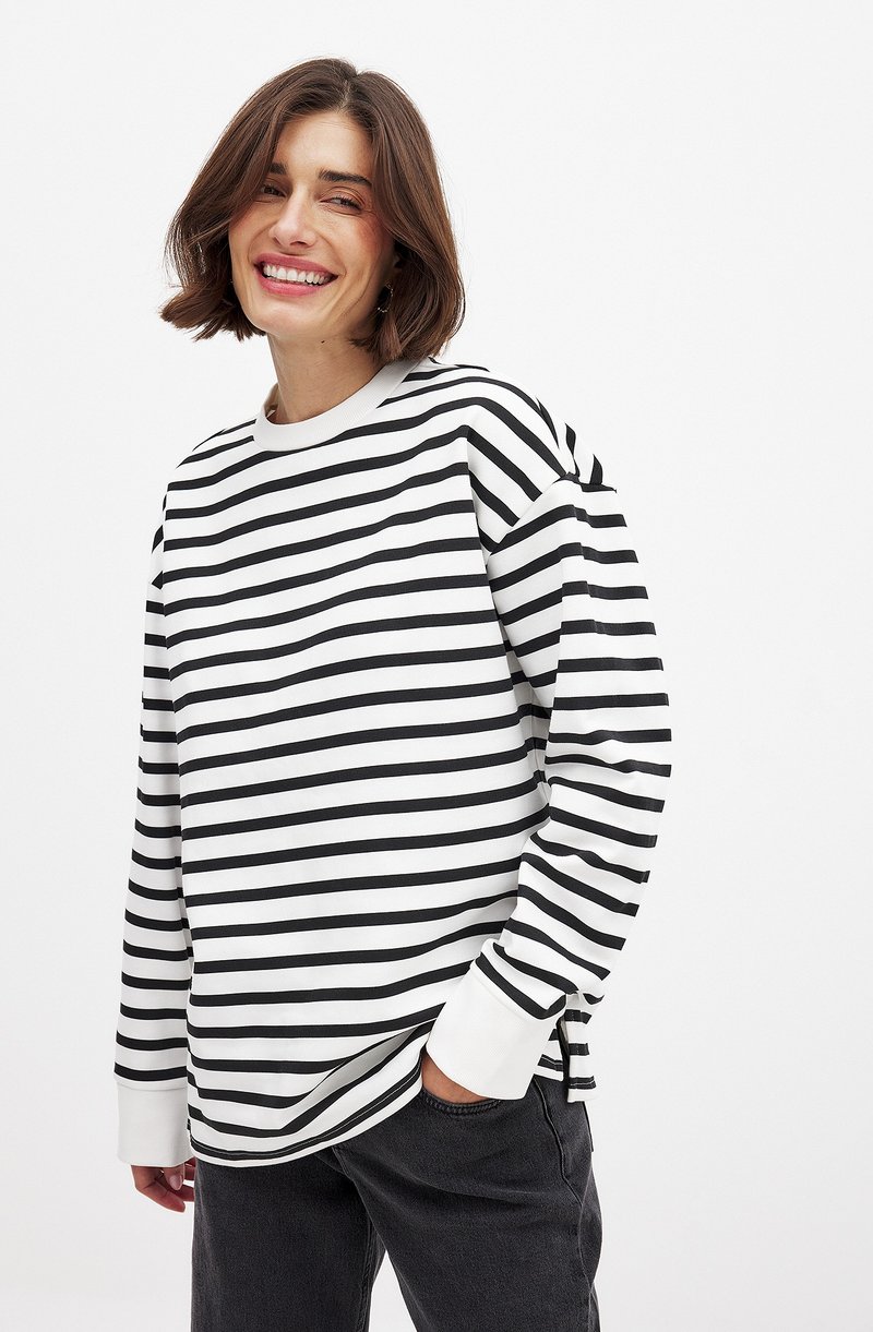 Sweatshirt à manches longues noir et blanc à rayures, avec un col rond. Tissu doux, coupe décontractée, fentes latérales et poignets côtelés.