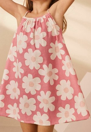 Vaaleanpunainen kesämekko, jossa on rento leikkaus. Mekossa on suuria valkoisia päivänkakkaroita persikkakeskellä, säädettävät hihnat ja röyhelökaula-aukko.