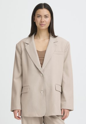 Beiger, übergroßer Blazer aus glattem Stoff mit einreihiger Knopfleiste, zwei Fronttaschen und Revers mit Kerbkragen.