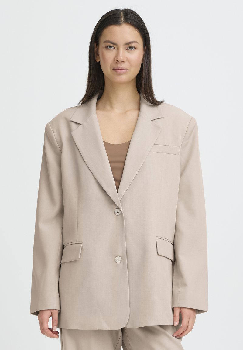 Beige, oversized blazer made of smooth fabric, featuring a single-button closure, two front pockets, and notch lapels.