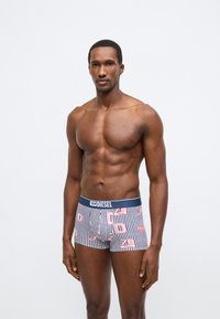 Férfi boxeralsó tengerészkék-fehér csíkos mintával és rózsaszín grafikai elemekkel. Puha anyag, elasztikus derékpánt Diesel logóval, testre szabott fazon.