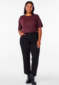 Burgundska kratka majica z kratkimi rokavi ima teksturirano tkanino; ujemajo se z visokim črnim jeansom in črnimi gležnjarji. Preprost, sproščen videz.