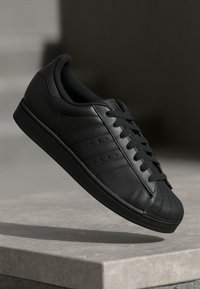 Baskets en cuir noir avec une finition lisse, un design à lacets, des détails perforés sur les côtés et un embout en caoutchouc. Construction légère.