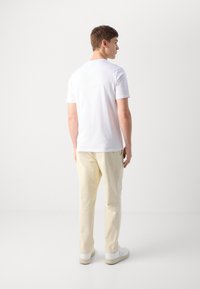 Hvid bomuld t-shirt med en klassisk pasform, kombineret med cremede bukser. Minimalistisk design, ensartet tekstur og uden synlige mønstre eller logoer.