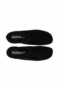 Sorte ruskindssko med rund tå, snørebåndsdesign, tonal syning og en hvid "BIANCO"-logo på indersålen.