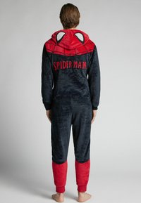 Mono de forro polar rojo y negro con capucha con diseño de Spider-Man, cremallera frontal y puños acanalados en los tobillos y las muñecas.