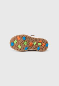 Semelle de chaussure en caoutchouc marron avec un motif hexagonal, incluant des accents colorés en orange, vert, bleu, ainsi qu'un graphisme de lézard.
