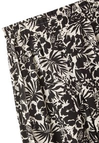 Tessuto plissettato floreale in bianco e nero con grandi foglie e fiori, dalla consistenza liscia e con una vita elasticizzata nella parte superiore.