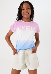 Katoenen T-shirt met een verloop van roze naar blauw, met "PALM BEACH" in witte tekst. Gepaard met lichtbeige shorts met een gestrikt taille.