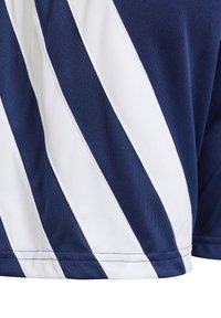 Camisa deportiva azul marino y blanca con rayas diagonales, fabricada con un tejido transpirable de textura suave y dobladillo cosido.