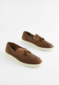 Hnědé kožené slip-on boty s tkaným vzorem a výřezy, s bílou gumovou podrážkou a dekorativními třásněmi.