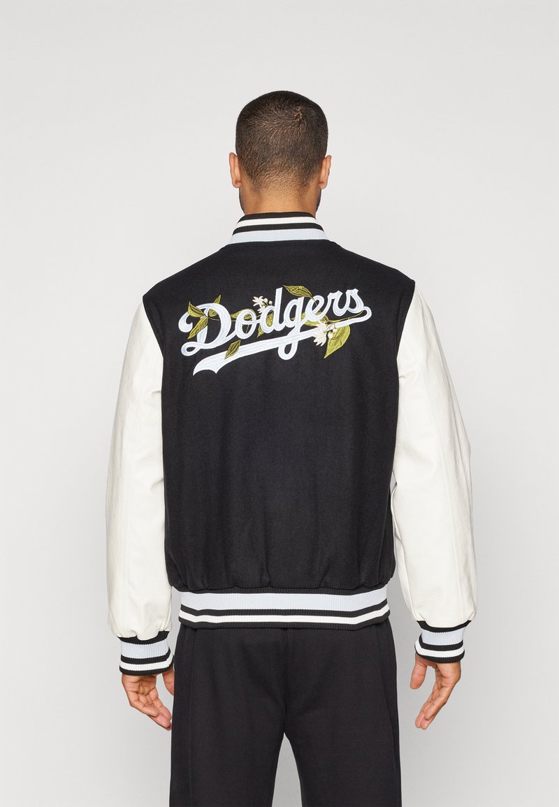 Svart og hvitt varsity-jakke med brodert "Dodgers"-logo og blomsterdetaljer, ribbestrikkede mansjetter og kant, med ullkropp og lærermte.