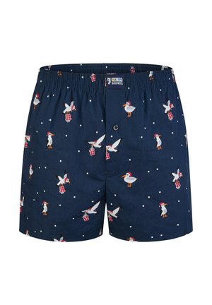 Navy blue shorts featuring a pattern of seagulls wearing red hats and holding gifts, with white dots scattered throughout the fabric. Elastic waistband.
