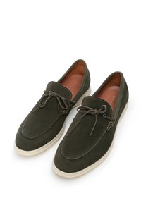 Mocassini in suede verde scuro con suole in gomma crema, dotati di un design con lacci e dettagli di cucitura sottili. L'interno presenta una finitura in pelle liscia.