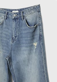 Ljusblå denimjeans med hög midja, slitna detaljer, två framfickor och knäppning, med fransade kanter.