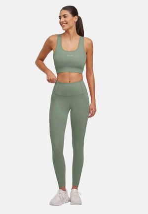 Sports bra and leggings set in light green, made from stretch fabric. Features seamless design, high waistband, and side pockets.