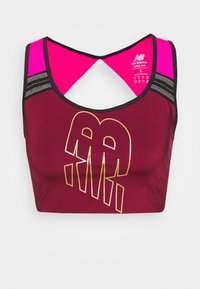 Burgundowy stanik sportowy z różowymi ramiączkami, z przeplatanym tyłem, ze złotym logo oraz poziomymi czarnymi paskami po bokach jako akcent.