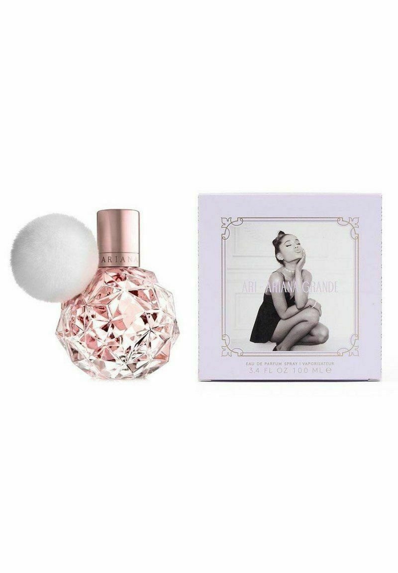 Vaaleanpunainen kristallimainen parfumipullo, jossa on pörröinen valkoinen pom-pom -korkki; laventelinvärinen laatikko, jossa on mustavalkoinen kuva ja yksityiskohtaista tekstiä. 3,4 fl oz.