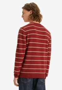 Rode trui met creme horizontale strepen, geribbelde halslijn en manchetten, zachte textuur, medium fit en een drop shoulder ontwerp.