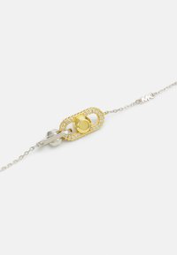 Sølv kædearmbånd med en guld oval lås med en flettet tekstur og en central rund accent omgivet af små klare ædelsten.