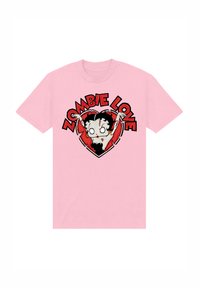 T-shirt in cotone rosa con un personaggio di cartone di uno zombie con capelli neri, occhi bianchi e un contorno a forma di cuore, il testo legge "ZOMBIE LOVE."