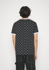 Black short-sleeve t-shirt with white geometric pattern and white ribbed collar. Soft fabric, relaxed fit, and subtle curved hem.
