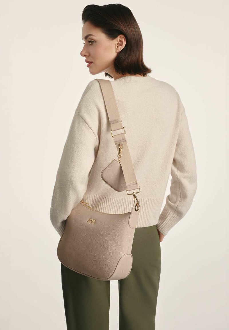 Beżowa skórzana torebka na ramię o teksturowanej powierzchni, ze złotymi elementami i regulowanym paskiem. Posiada boczny zamek błyskawiczny i małą załączoną kieszonkę.