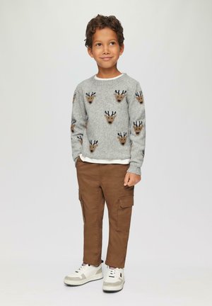 Grijze gebreide trui met rendierpatronen, bruine cargobroek en witte sneakers. De trui heeft een ronde halslijn en lange mouwen.