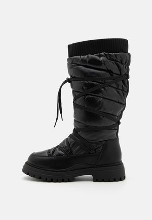 Black knee-high boots with a quilted texture, featuring a lace-up design, contrasting ribbed top cuff, and a thick, rugged sole.