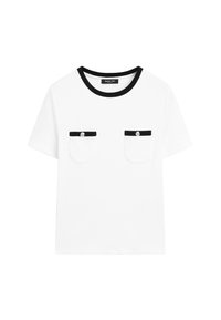 White T-shirt with a black round neckline, two chest pockets with black trim and silver buttons. Short sleeves, simple design.