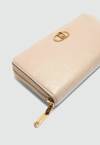 Beige Lederbörse mit strukturierter Oberfläche, goldenen Beschlägen und einem Reißverschluss. Verfügt über ein dekoratives Logo auf der Vorderseite.