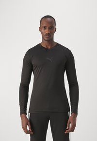 Czarna, długosleeve'owa koszulka sportowa wykonana z gładkiego materiału, z dekoltem w kształcie litery V i dyskretnym logo Pumy nadrukowanym na piersi. Płaskie szwy.