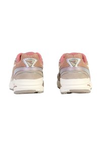 Scarpe da ginnastica di un morbido rosa pallido e beige, con pannelli in rete, colli imbottiti e suole bianche. Presentano un logo laterale e accenti testurizzati.