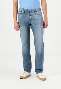 Lyseblå straight-leg jeans i denim, med standard liv, beltehemper og fem-lommers design, kombinert med hvite sneakers.