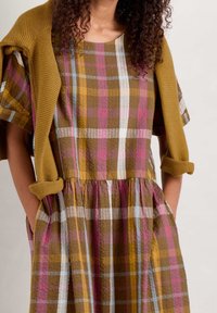 Hnědé a vícebarevné kostkované šaty s krátkým rukávem a nařaseným pasem, obsahující kapsy, doplněné hořčicovým žebrovaným cardiganem.
