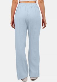 Lichtblauwe, gestructureerde, wijde broek met een elastische tailleband. De stof lijkt zacht en ademend, ideaal voor casual kleding.