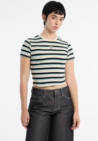 Gestreepte cropped t-shirt in lichtblauw, donkergroen en crème. Heeft een klein driehoekig logo op de borst en korte mouwen.