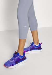 Buty sportowe Nike z wielokolorową cholewką w odcieniach niebieskiego i fioletowego, czarnymi akcentami, białą podeszwą i odblaskowymi detalami.