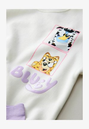 Sweat-shirt blanc avec deux graphismes d'animaux colorés, représentant un zèbre et un léopard, et le mot "BLUEY" en lettres violettes brillantes.