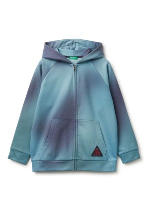 Sudadera con capucha y cremallera, con bolsillos frontales en un degradado de azul y gris, que presenta un pequeño parche triangular en el bolsillo inferior.
