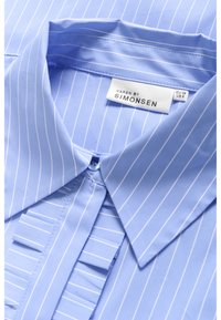 Light blue shirt featuring white vertical stripes, a pointed collar, and a placket with textured fabric accents. Brand label visible inside.