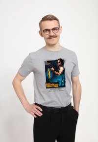 Grå bomulls t-shirt med en retro grafik från filmen "Escape from New York". Designen inkluderar färger som blått, gult och svart.