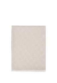 Tela rectangular beige con un sutil patrón geométrico y bordes con flecos, doblada cuidadosamente sobre un fondo blanco.